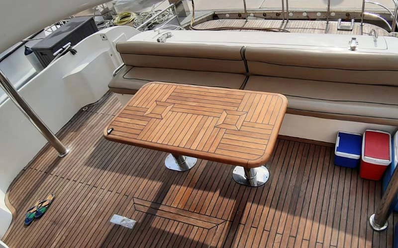 صالون رئيسي على متن Range Yacht مع نوافذ بانورامية واسعة وأرائك من القماش باللون البيج وأرضيات من خشب البلوط وطاولة قهوة بسيطة في المنتصف - مصممة للاسترخاء على شاطئ المحيط