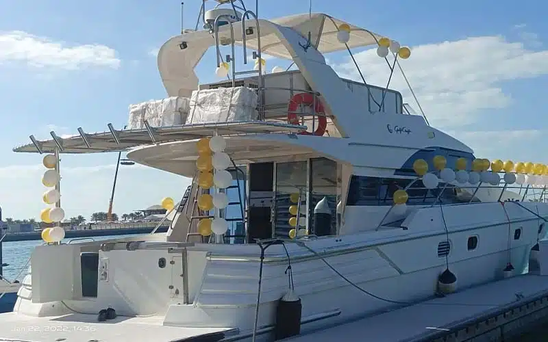 منظر جانبي لليخت Sun Rise Yacht الراسي على طول الساحل مع ضوء الصباح الباكر الذي يسلط الضوء على مظهره الخارجي الأنيق وجسر الطيران