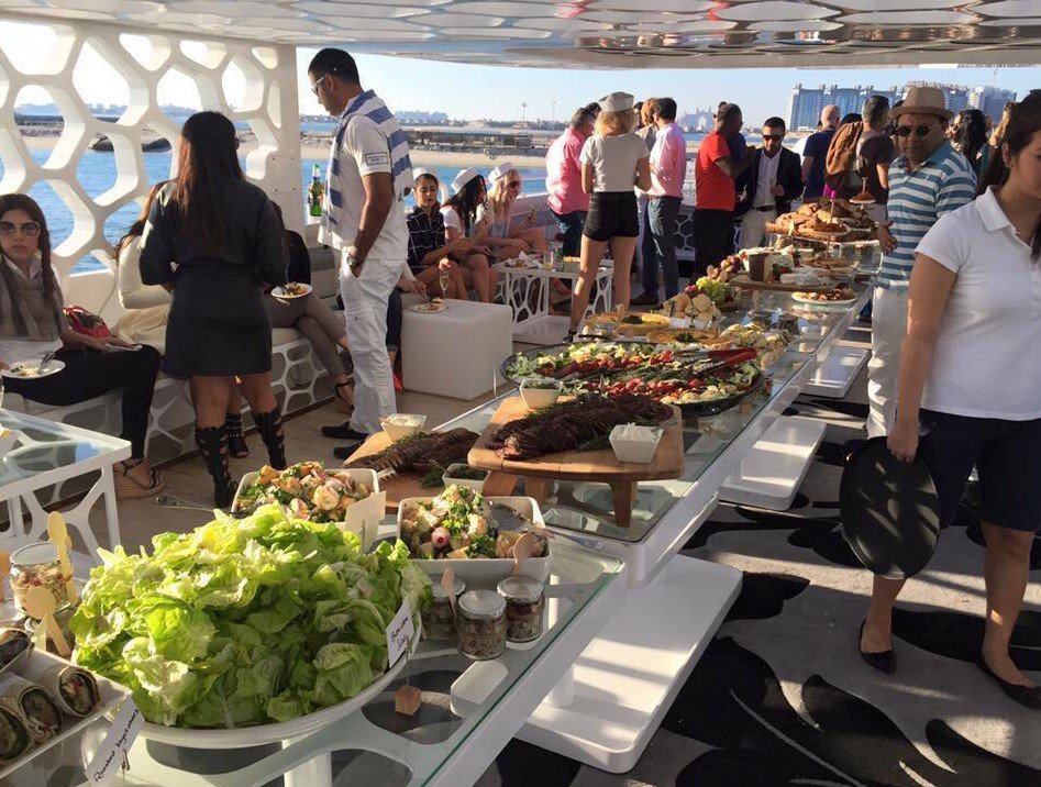 Guests circulating around a yacht buffet of salads, meats and shared dishes