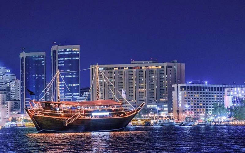Night view of Al Mansour Yacht fully illuminated and cruising in Dubai – exclusive dinner cruise from Mala Yachts yacht rental Dubai