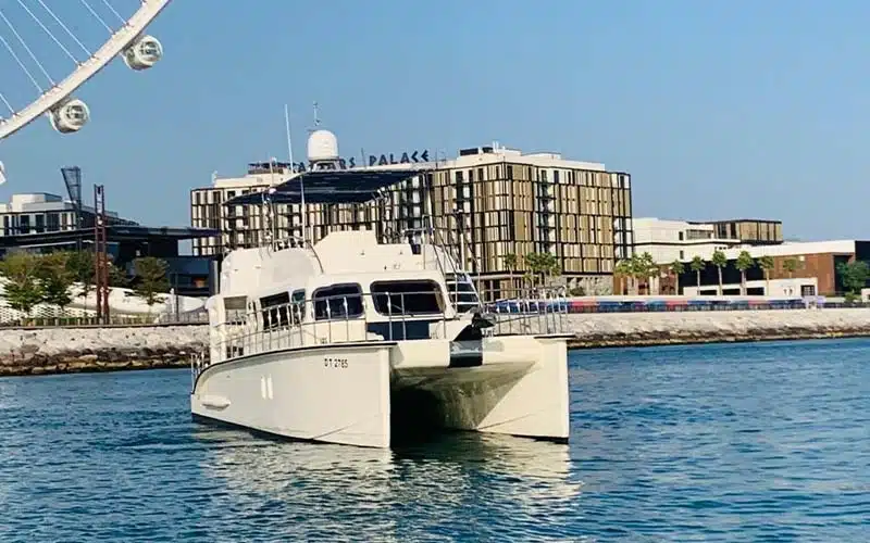 Sunlit aft deck view of catamaran showing wide swim platform, outdoor seating under canopy, and water toys stowed