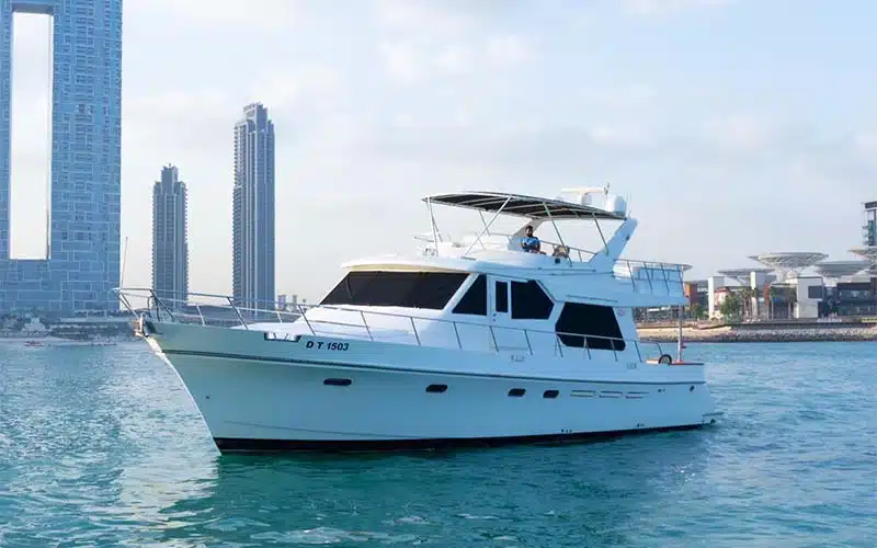 Side profile of Gulf King Yacht cruising through calm waters with its sleek white hull and flybridge deck in full view