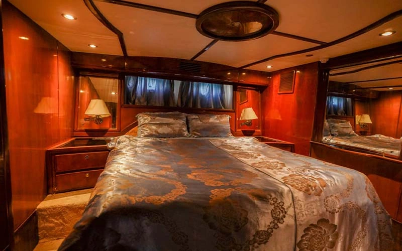 Master stateroom on RJ Range yacht featuring a king-size bed, light-toned oak paneling, rosewood accents, wardrobe, vanity area, and a private office nook visible through a sliding wall
