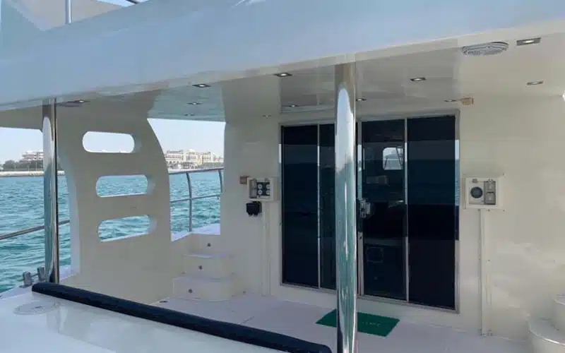 Main salon of Cat Man Yacht featuring a modern open-plan layout with plush sofas, dining table, and wrap-around windows offering ocean views