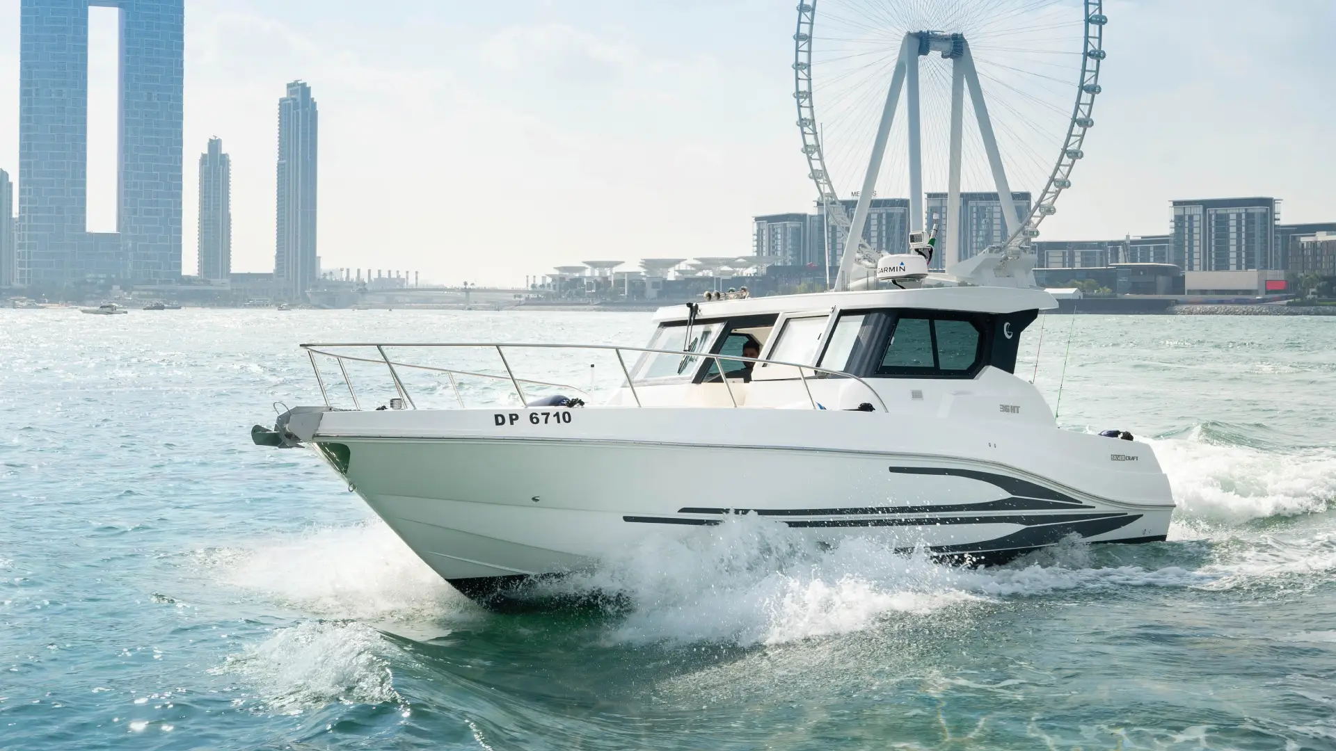 The 36ft yacht Dubai from Malayachts.ae cruising in the waters of Dubai, with the Ain Dubai in the background.