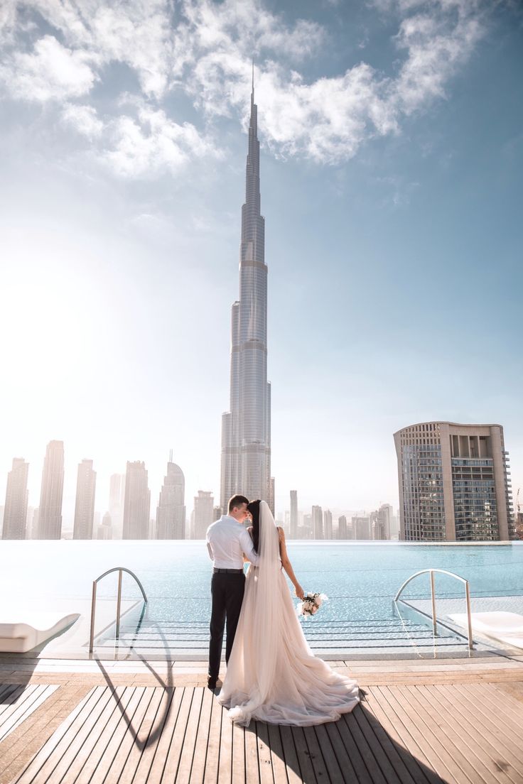 Bride and groom embracing by infinity pool with stunning view of Burj Khalifa and Dubai skyline in the background