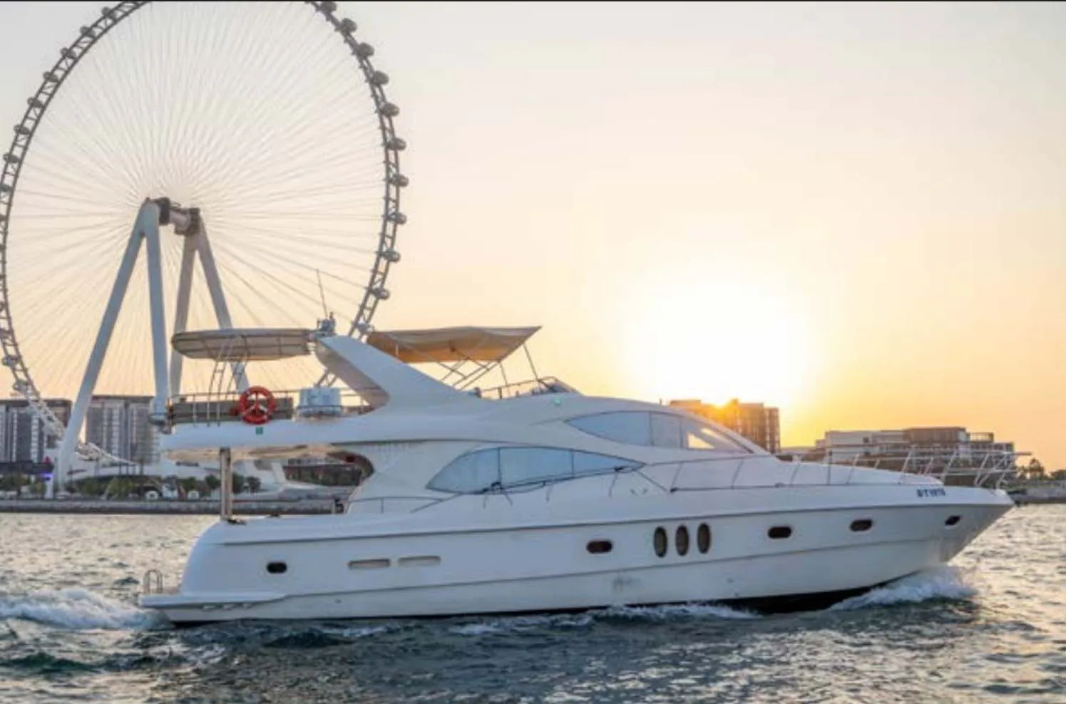 Luxury yacht cruising at sunset near Ain Dubai with golden sky and calm waters