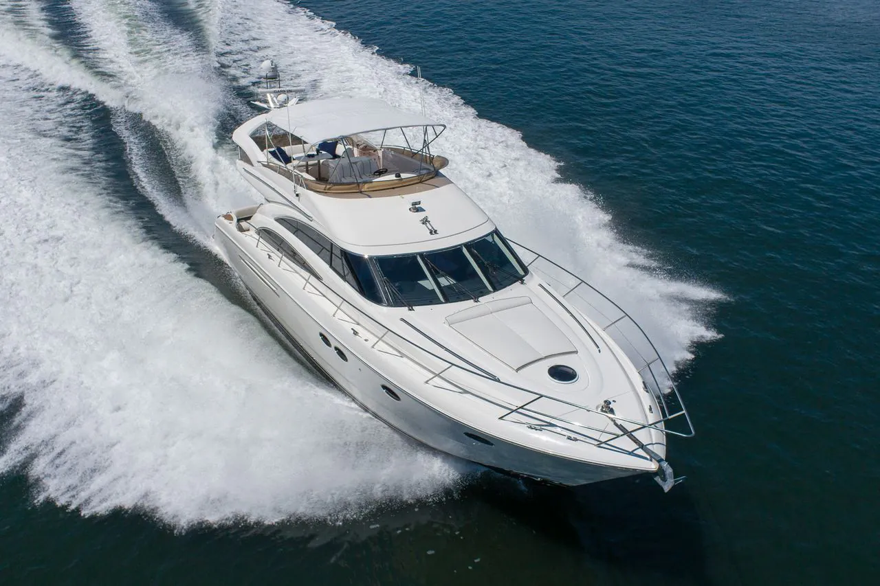 Luxury motor yacht speeding across open waters, creating white wake trails behind.