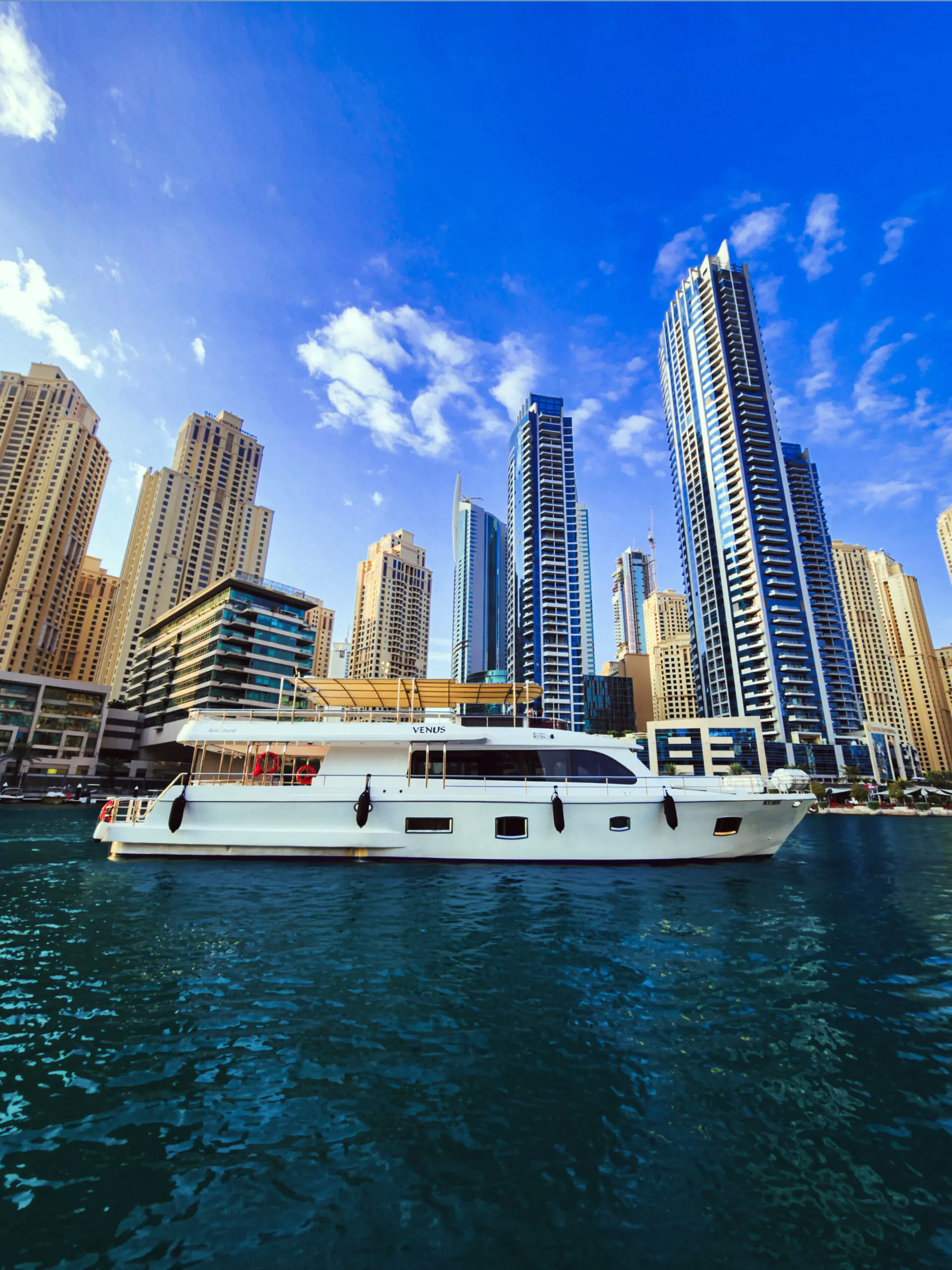 Luxury yacht cruising in Dubai Marina with towering skyscrapers and calm waters
