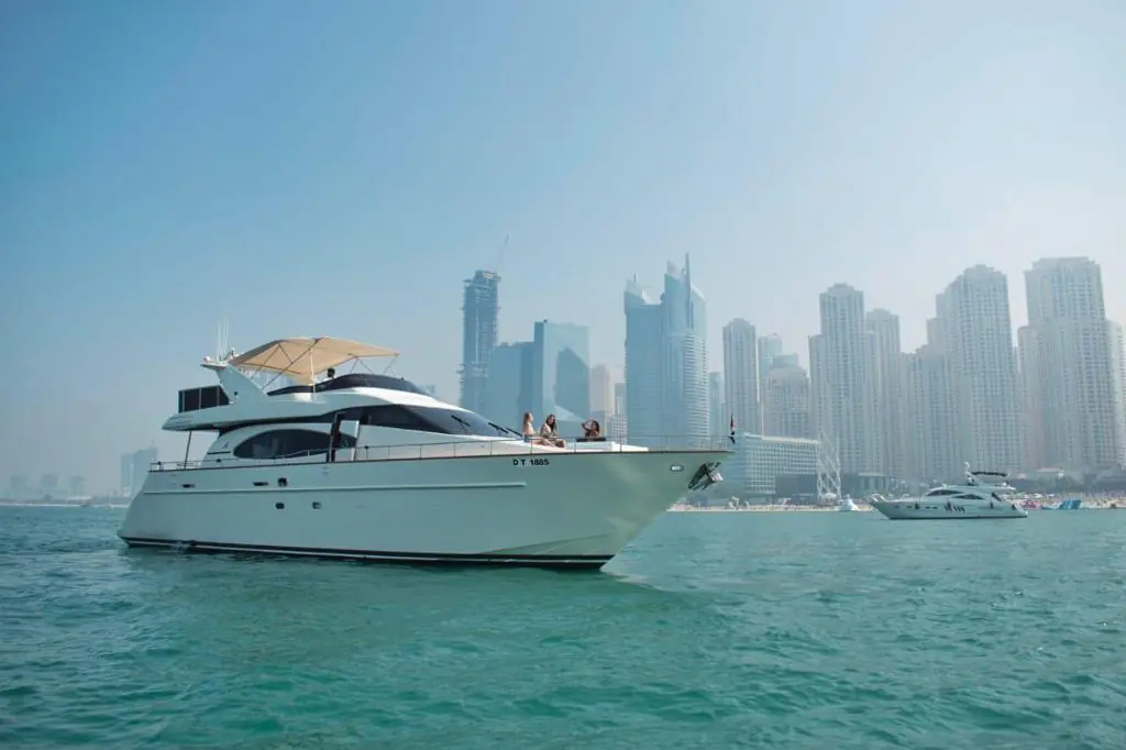 Luxury yacht cruising in Dubai Marina with modern skyline and calm blue waters.