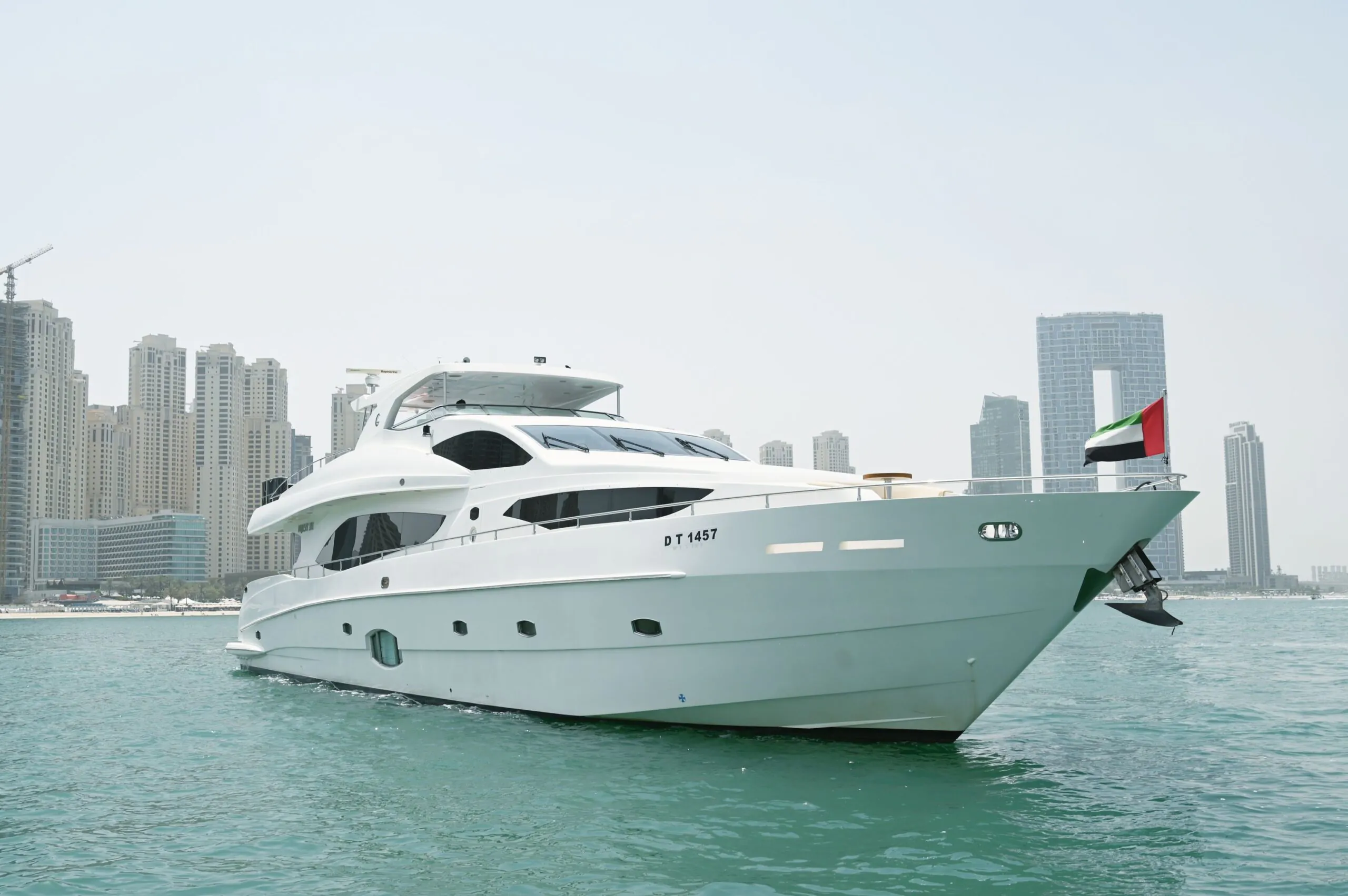 Luxury white yacht cruising in Dubai Marina with modern skyline and calm waters
