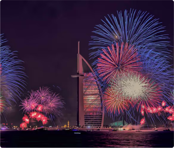 Colorful fireworks lighting up the Dubai skyline near Burj Al Arab at night, reflected over the Arabian Gulf.