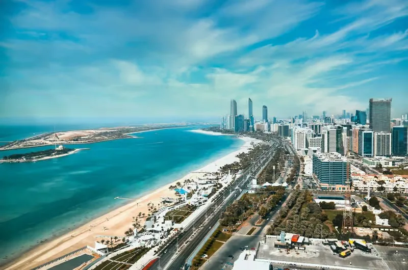 Corniche Promenade from the water Aerial view of Abu Dhabi Corniche beach, waterfront road and skyline seen from a yacht cruise route