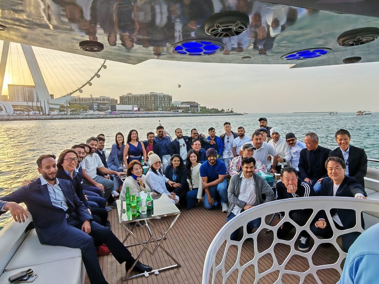 Majid Al Futtaim team gathered on the aft deck of a Mala Yachts charter in Dubai at sunset, with Ain Dubai behind them